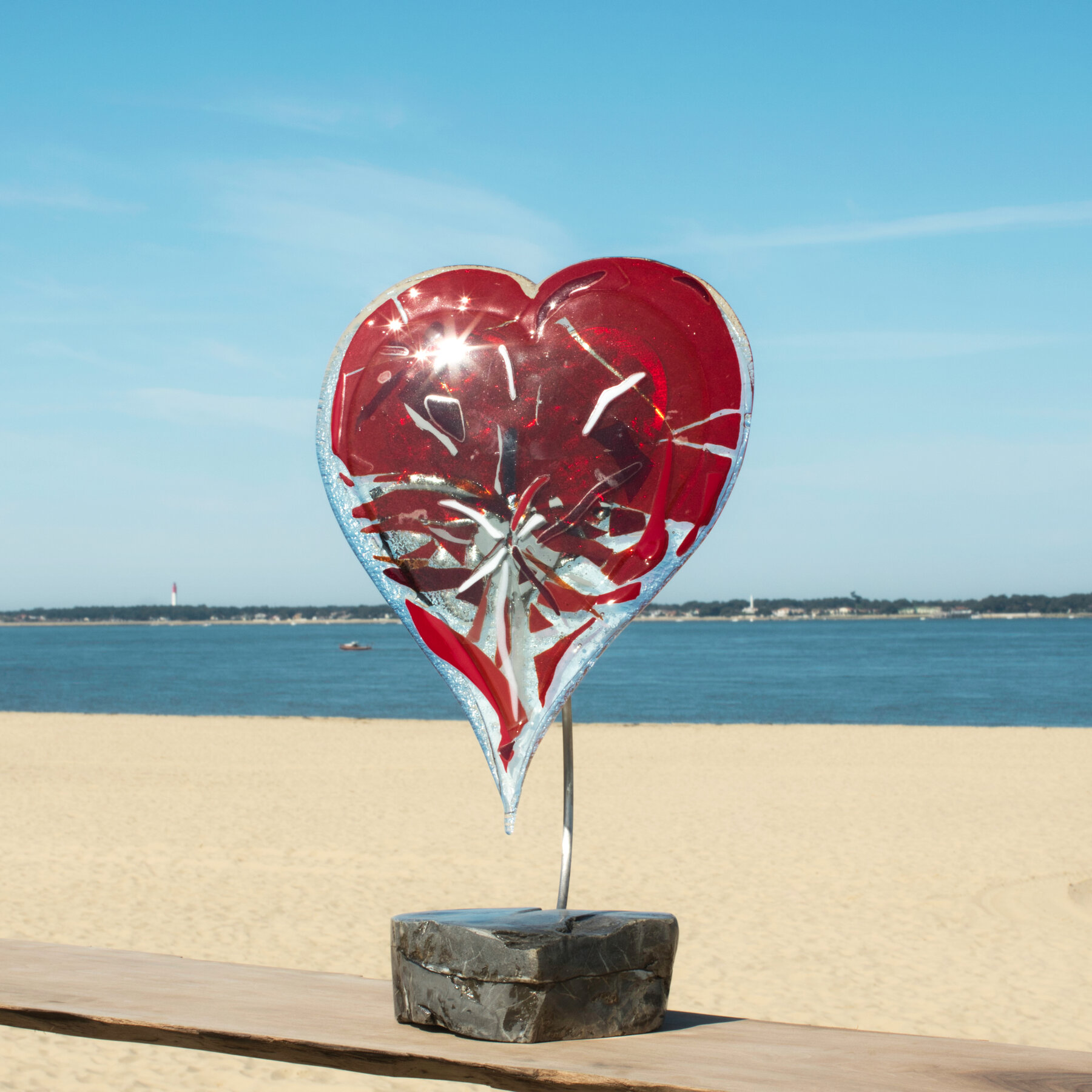Cœur en verre fusionné rouge sur socle de pierre, devant le Bassin d'Arcachon